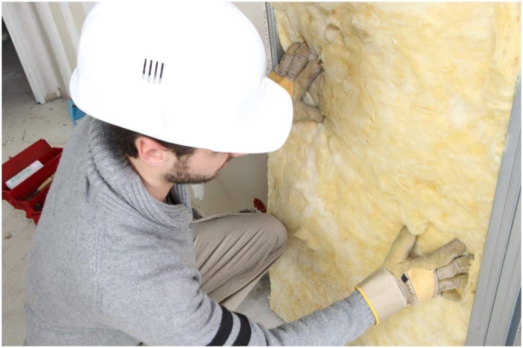 man installing insulation in wall