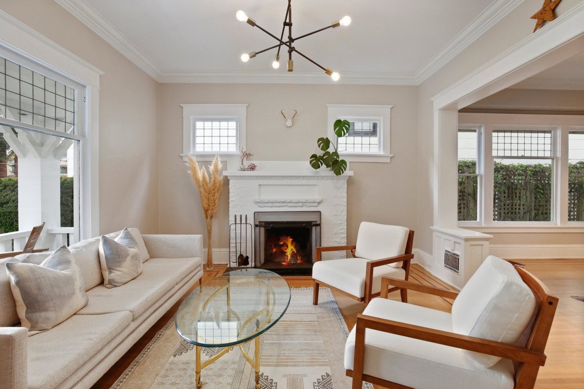 A neutral colored living room with a fireplace, 2 chairs, and a sofa