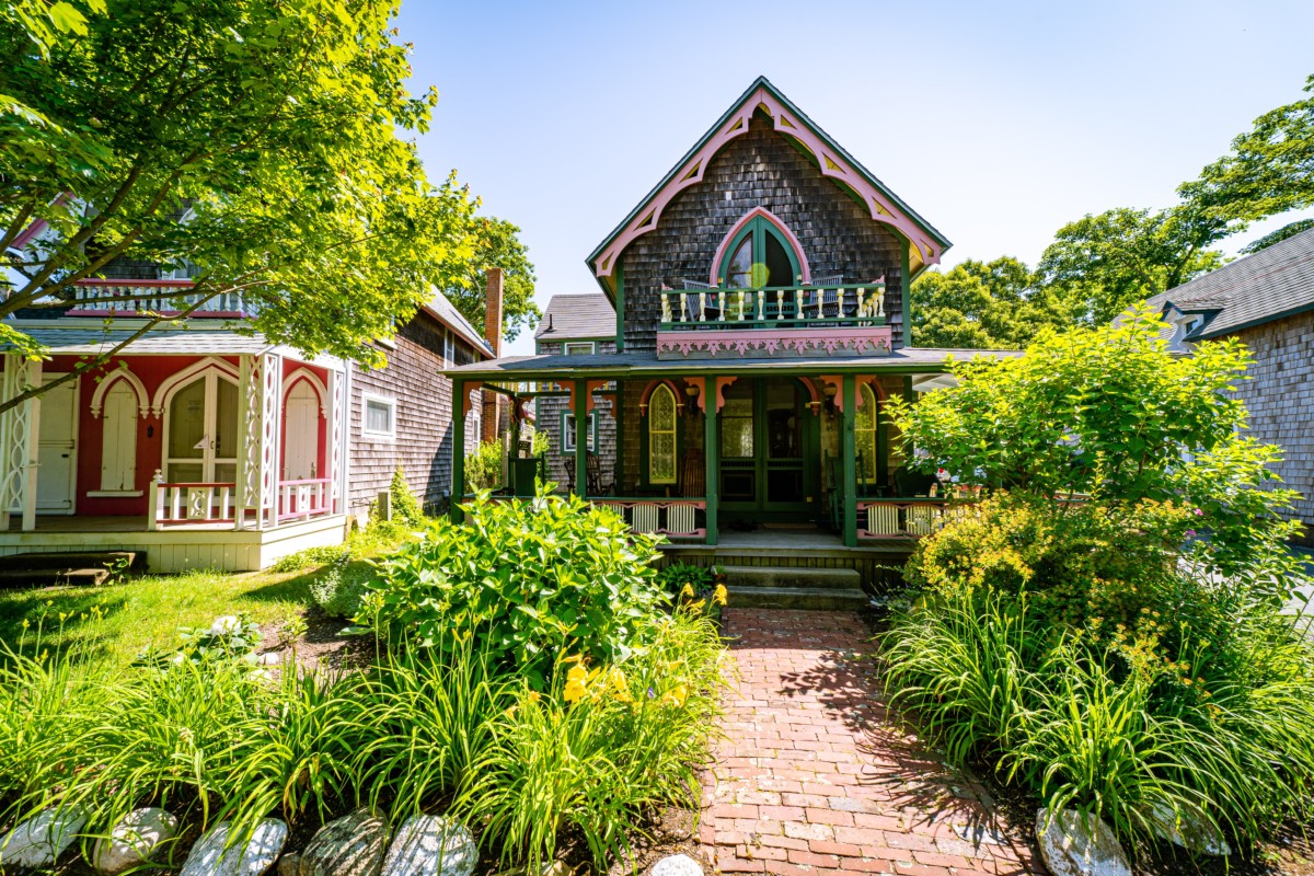 gothic revival style victorian house with greenery in the front yard and brightly colored trim on the home