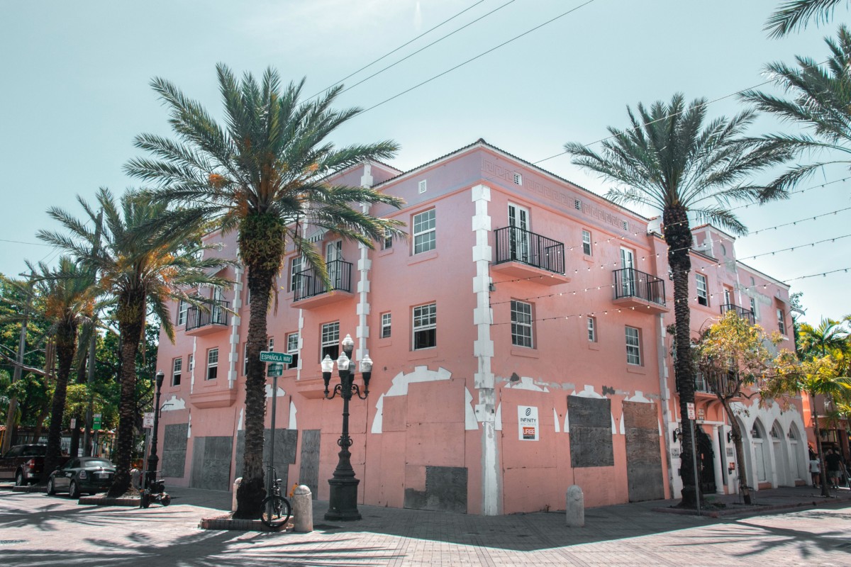 affordable miami suburbs with a peach colored building and palm trees with a blue sky