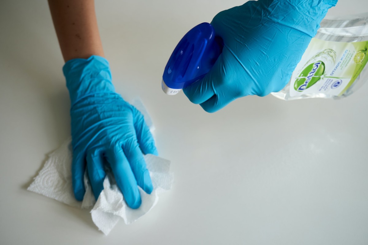 person wearing rubber gloves while cleaning mold