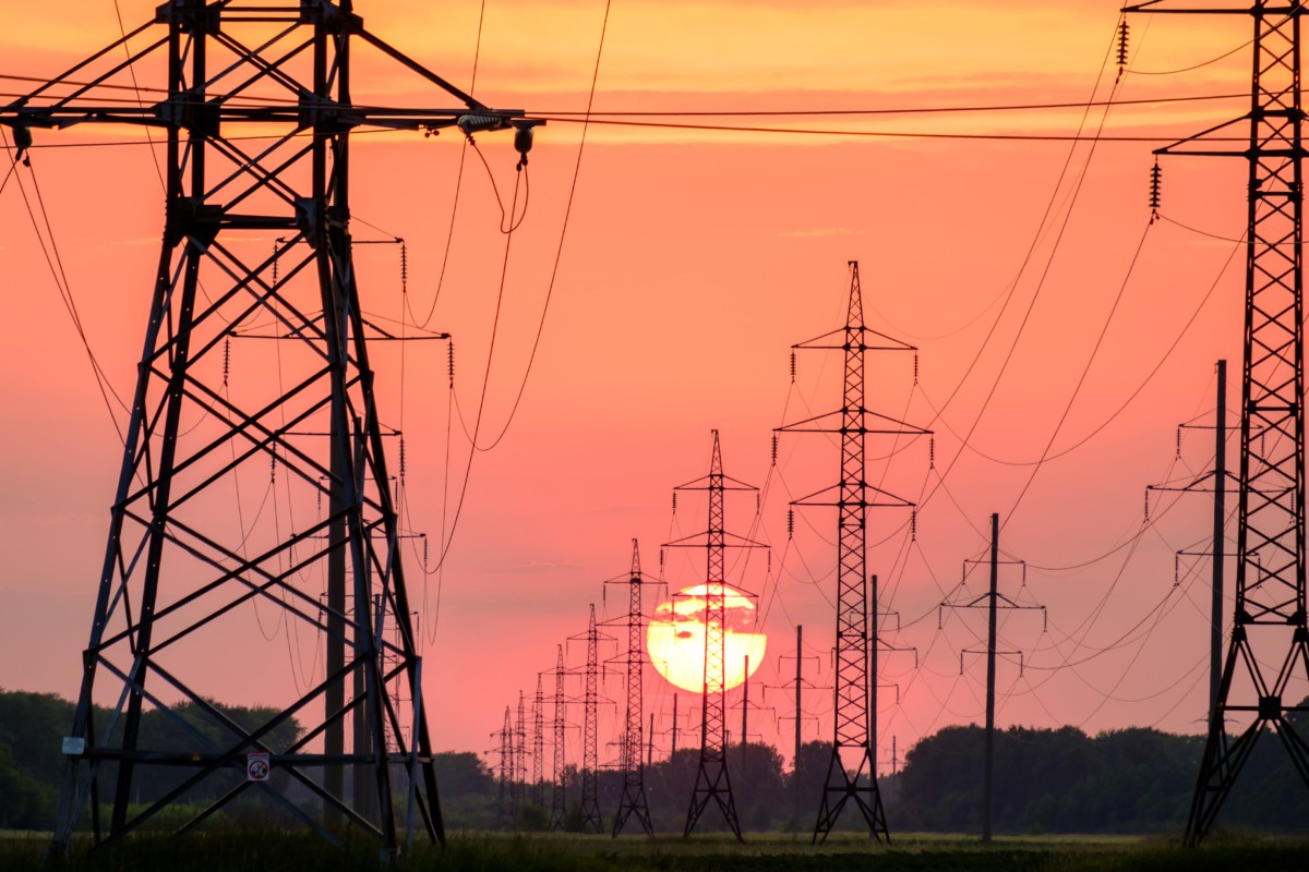 power lines on a field during sunset