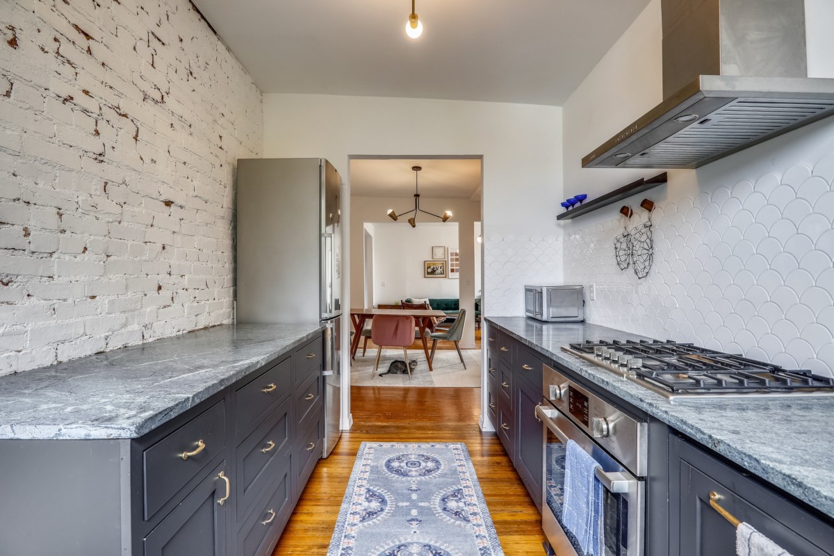Galley kitchen with an exposed brick wall and gray cabinets