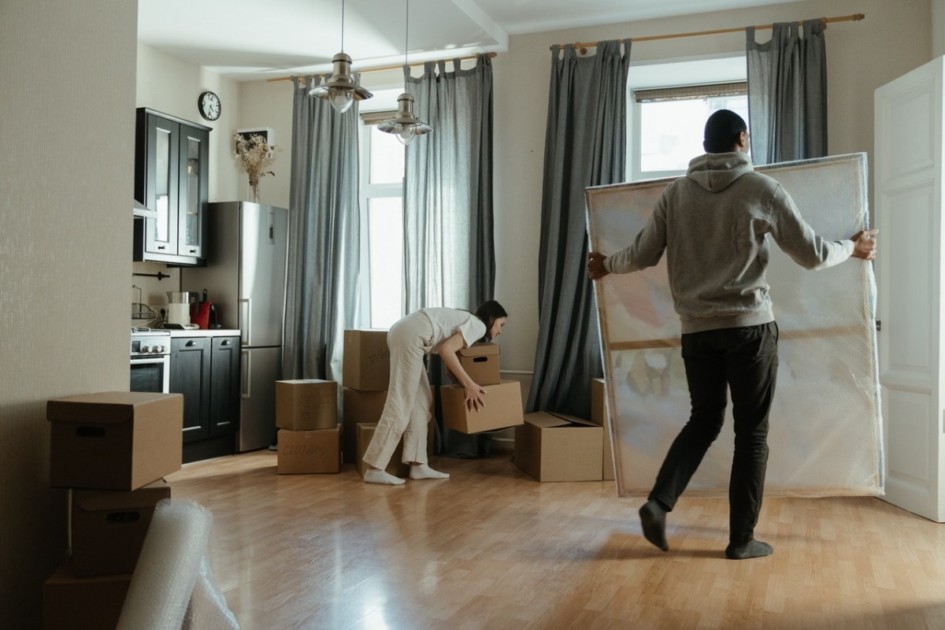 Two people moving boxes into a new apartment