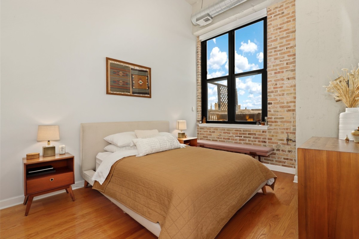 one bedroom with exposed brick wall, a window, and brown furnishings